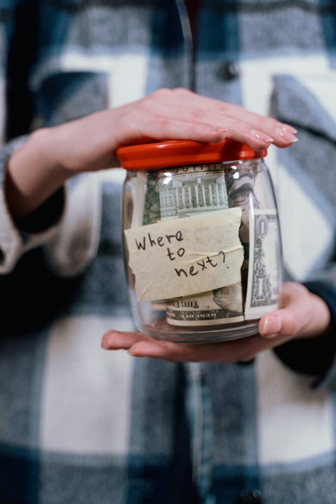 pexels-photo-7009477 A person holds a savings jar filled with money and a note that says 'Where to next?' symbolizing travel savings.